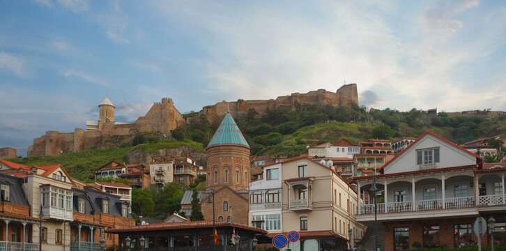 Landscape of historical Tbilisi street with fortress, mountains and blue sky on the background