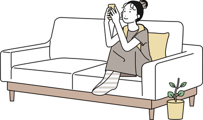 家のソファでスマホを触る女性