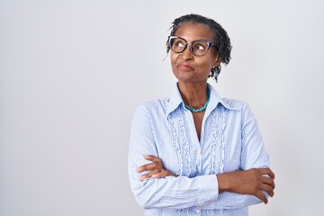 African woman with dreadlocks standing over white background wearing glasses smiling looking to the...