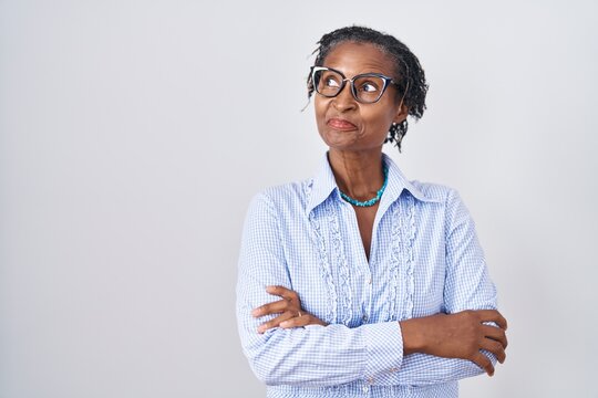 African woman with dreadlocks standing over white background wearing glasses smiling looking to the side and staring away thinking.