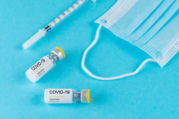 Coronavirus vaccine vial glass with a syringe on blue background. Covid-19 medicine vaccination...