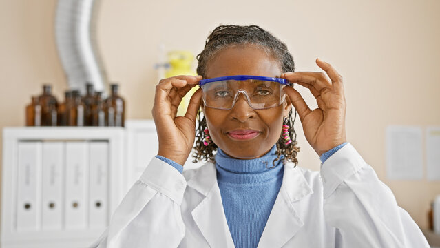 African american woman scientist adjusting safety glasses in a laboratory setting, showcasing professionalism and expertise.