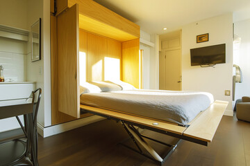 Fototapeta na wymiar murphy bed being lowered in a minimalist studio apartment