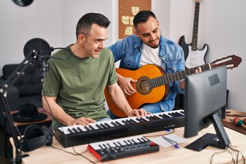 Two men musicians playing piano and classical guitar at music studio