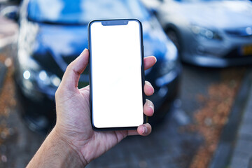 Man holding smartphone showing white blank screen at car parking