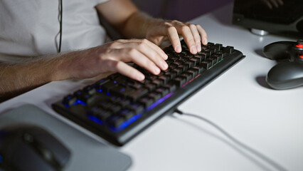 Caucasian man typing on a backlit keyboard in a dark room at night, showing a focus on technology and modern home office.