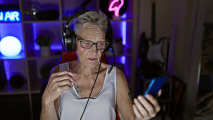 Tech-savvy, grey-haired senior woman enthrals gaming world as she streams live video call, gamepad...