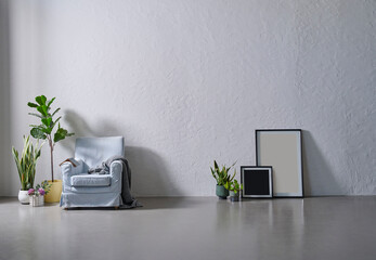 Grey stone wall background, frame, vase of green plant, sofa armchair blanket style, modern room.