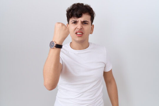 Young non binary man wearing casual white t shirt angry and mad raising fist frustrated and furious while shouting with anger. rage and aggressive concept.