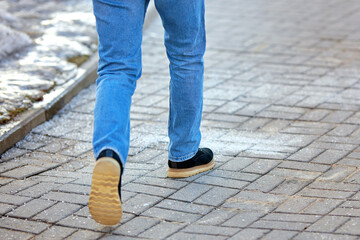 Man walking on sidewalk covered with rock salt and sand, prevent slipping. Salt sprinkled on paving...