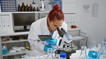 Smitten by science, gorgeous young redhead woman scientist in lab, immersed in bio research with...