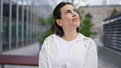 Beautiful young hispanic woman smiling confident looking to the side in the streets of Stockholm