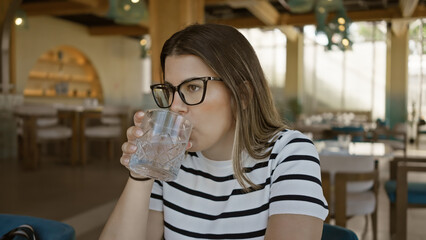 Adult woman drinking water in a modern cafe