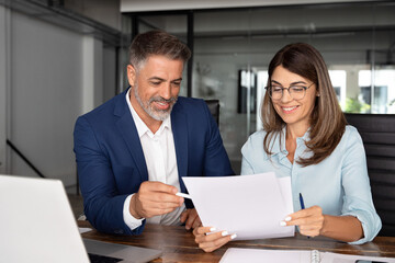 Team of diverse partners mature Latin business man and European business woman discussing project...