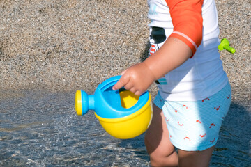 playing on the beach at the sunset time. baby playing with water on sea shore. closeup of the hand...