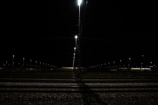 Freight station at night in Zurich, Spreitenbach. Freight trains are illuminated by bright headlights. In the background is a light layer of fog.