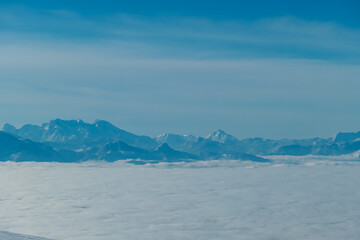 Scenic view of fog covered Lavanttal valley surrounded by snow capped mountain peaks Karawanks and Julian Alps seen from top of Grosser Speikkogel, Kor Alps, Lavanttal Alps, Carinthia Styria, Austria