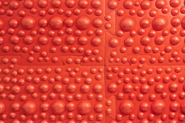 Close-up of a red massage mat with hemispherical working ridges. Several elements are fastened with dovetail locks. Background. Texture.