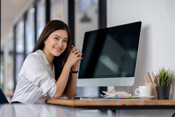 Asian business woman using computer with empty blank screen, sitting at workplace in the office,...