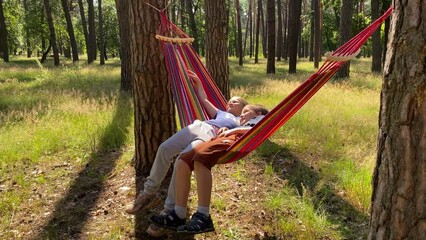A family embarks on a delightful outdoor adventure. Bonding over the shared joy of camping at sunny day. Children relax in hammocks, chatting and admiring the beauty of nature in the serene forest
