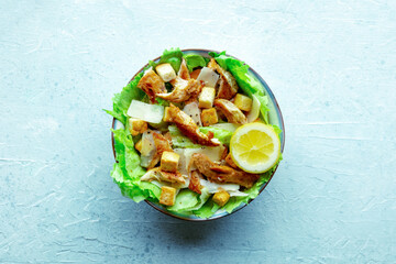 Caesar salad with chicken breast, lettuce, croutons, and a lemon, overhead flat lay shot on a slate background - 739967956