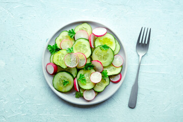 Fresh cucumber and radish salad with parsley, overhead flat lay shot with a fork. Simple vegan recipe on a slate background. Healthy diet - 739968396