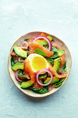 Salmon, avocado and egg salad with fresh leaves and onions, overhead flat lay shot on a slate background. Healthy diet, top view