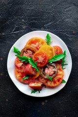 Fresh tomato and rocket salad. A variety of tomatoes of different sorts, shot from above with arugula leaves. Healthy summer food, top shot - 739968748
