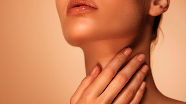 Graceful female fingers touch the neck, delicate skin of an even color on an isolated beige background. Skin care.