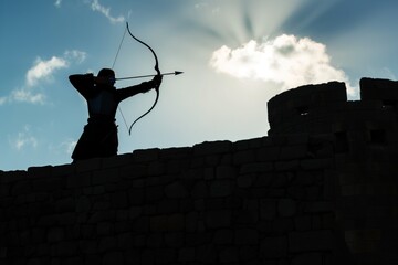 archer silhouetted against sky on fortress wall - obrazy, fototapety, plakaty