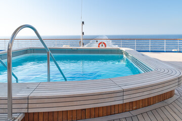 A swimming pool with clear, clean water at the stern of a cruise ship with a view of the ship's...