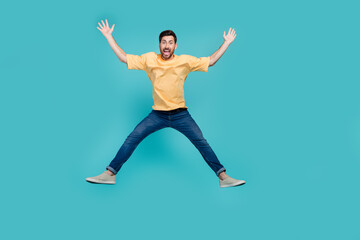Full body length photo of active man in yellow t shirt and jeans raised hands up seems like star figure isolated on blue color background