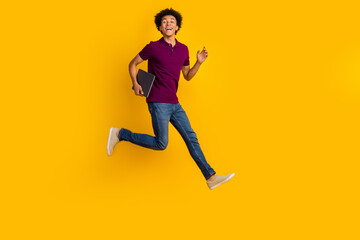 Fototapeta na wymiar Full length photo of glad attractive man wear trendy nice violet clothes hold netbook running work isolated on yellow color background