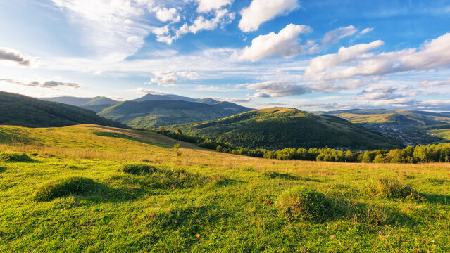 rural landscape with grassy meadows. distant mountain range beneath a sky with clouds. beautiful scenery of carpathian countryside on a sunny day in early autumn