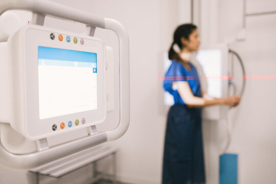 Medical professional standing by digital x-ray equipment