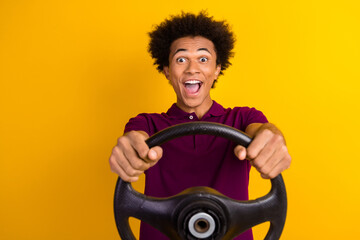Photo of cheerful excited amazed man wear purple trendy clothes hold wheel riding fast test drive isolated on yellow color background