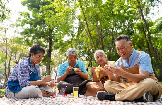 A group of Asian senior people enjoy painting cactus pots and recreational activity or therapy outdoors together  at an elderly healthcare center, Lifestyle concepts about seniority - Powered by Adobe
