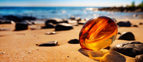 Amber on sand on the beach in sunshine - obrazy, fototapety, plakaty