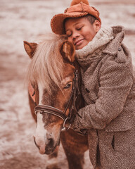 the boy gently hugs the pony with his eyes closed