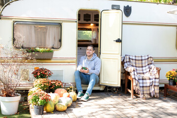 Campsite on caravan or camper van in forest. Rest man sitting on the doorstep of the motor home...