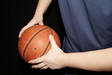 hands of a basketball player hold the ball to the side, shielding the ball in basketball, individual technique of shielding the ball in basketball on a black background, close-up, basketball training