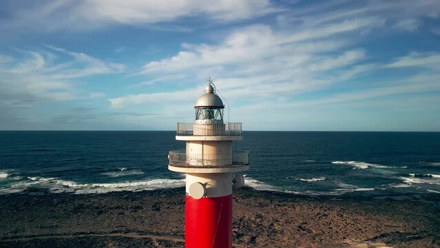 The 19th century red and white bands Faro del Tost&oacute;n lighthouse located on the northwest coast of Fuerteventura in the Canary Islands. A lighthouse against the background of the blue sky and the ocean
