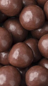Vertical video. Closeup of chocolate malted balls. Candy backdrop