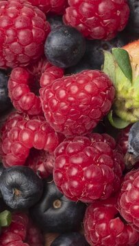 Vertical video. Berries closeup backdrop. Strawberry, raspberry and bluberry