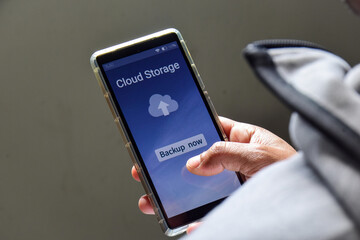 Person using his smartphone to upload and backup files to online storage or cloud storage service.