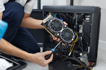 Man is holding a computer video card in his hands. Computer maintenance.