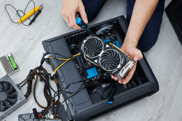Man is holding a computer video card in his hands. Computer maintenance.