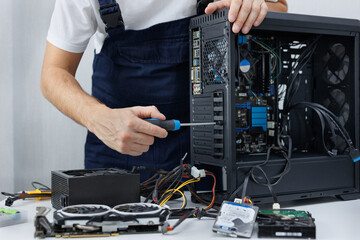 Closeup computer technician holding a screwdriver and repairing a pc.