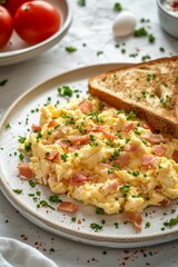 A delicious serving of scrambled eggs with ham and herbs, accompanied by a slice of toasted bread