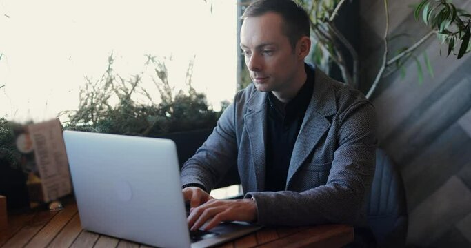 A man in classical suit working by laptop in a cafe